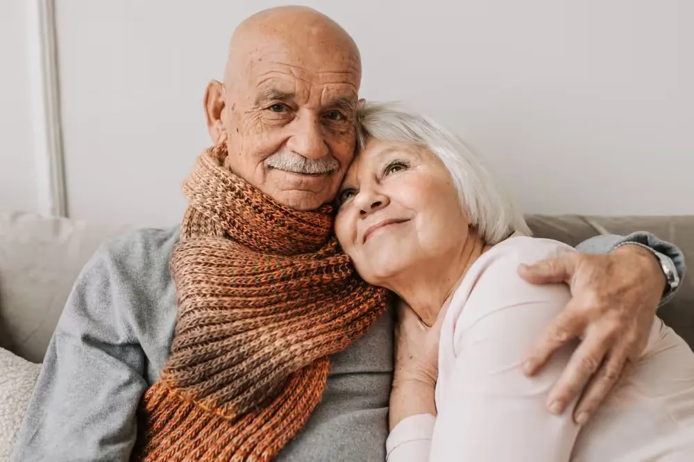 An older couple sitting close together on a couch at home